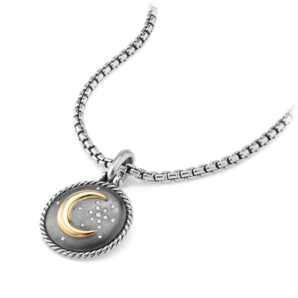 A silver necklace features a pendant with a two-tone design. The pendant has a twisted silver border, a brushed metal background, and shows a gold crescent moon accompanied by tiny silver stars. The chain is a box chain style, adding a modern touch to the accessory.