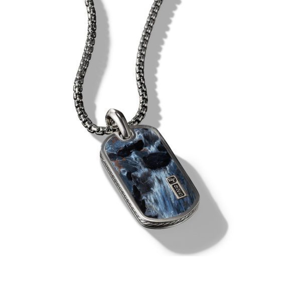 A silver chain necklace with a rectangular pendant featuring a blue and black marbled design. The pendant has a small silver plaque with an engraved symbol. The background is white with the pendant casting a shadow.