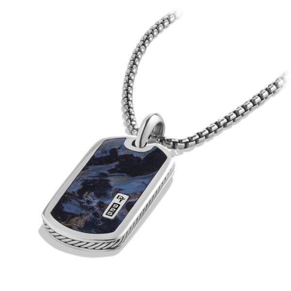 A silver dog tag necklace featuring a black and blue marbled inlay and a small metal plate engraved with "NV", attached to a sleek, braided chain.