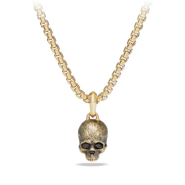 A gold necklace with a chain link design featuring a pendant shaped like a skull. The skull pendant has a textured surface, adding an antique appearance. The necklace is displayed against a white background.