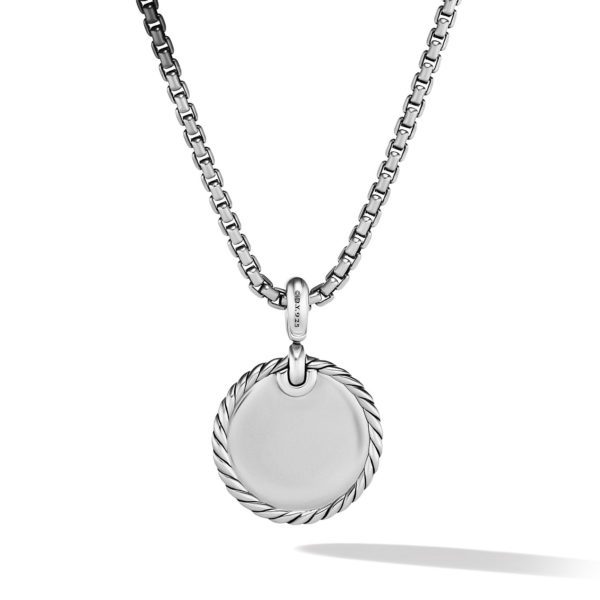 A silver necklace with a round pendant. The pendant has a simple, smooth surface with a twisted rope design around the edge. The chain features evenly spaced rectangular links. The necklace casts a subtle shadow on a plain white background.