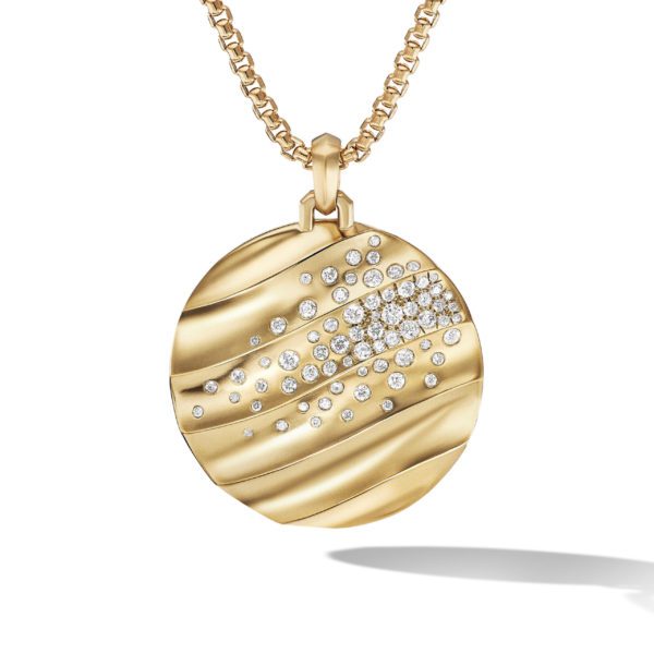 A round gold pendant with wavy, textured engravings adorned with scattered small diamonds hangs from a gold chain. The pendant casts a soft shadow below it.