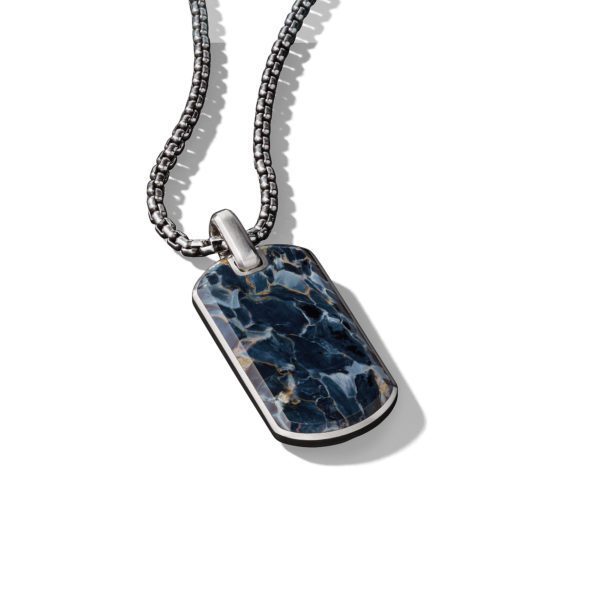 A silver chain necklace with a rectangular pendant featuring a polished, marbled blue and white stone. The pendant has a shiny silver border. The picture is taken against a plain white background, highlighting the intricate details of the stone and chain.