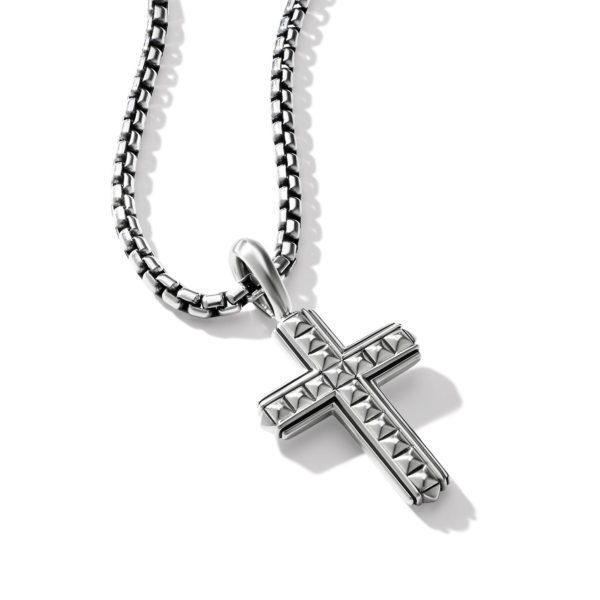 A close-up image of a silver cross pendant hanging on a matching chain. The cross features a textured design with small pyramid-shaped studs covering its surface. The necklace is set against a plain white background.