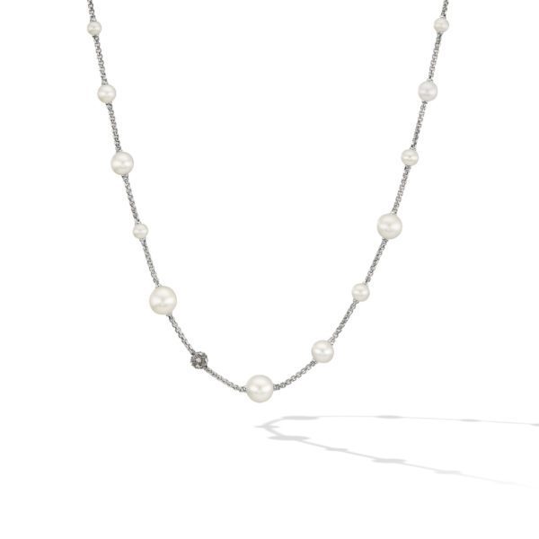 A delicate necklace featuring pearls of varying sizes, spaced along a thin silver chain. The arrangement is asymmetrical, lending a subtle elegance to the piece. The necklace casts a faint shadow on the white background.