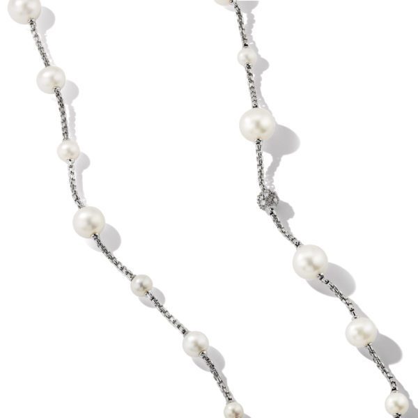 A delicate necklace featuring white pearls strung along a thin, silver chain. The pearls are spaced intermittently along the length of the chain, creating an elegant and simple design. The background is white, highlighting the necklace's details.