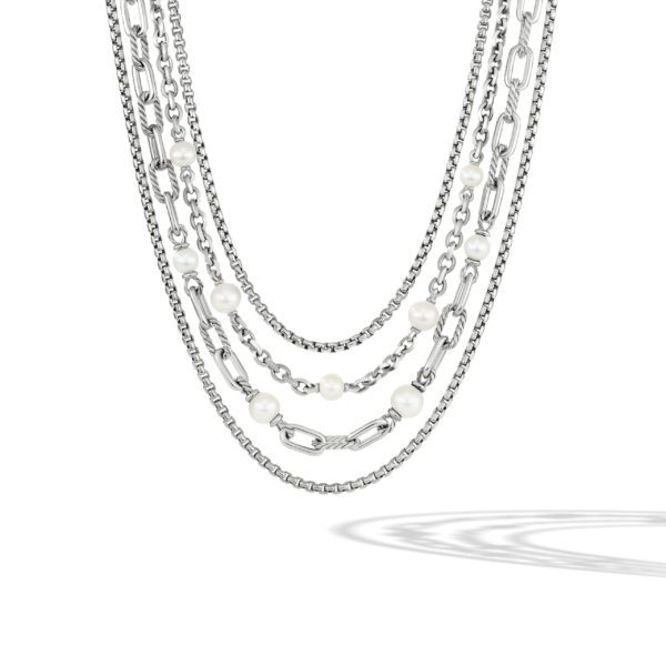 A multi-strand necklace featuring a combination of silver chains and white pearls. The design includes a variety of chain styles, including a chunky link chain and thinner, more delicate chains, with evenly spaced pearls. The necklace casts a shadow on a white background.