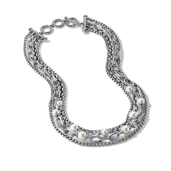 A silver chain necklace with multiple layers intertwined and adorned with pearl accents, forming a sophisticated and elegant design. The necklace features various types of chain links, creating a textured and intricate appearance.