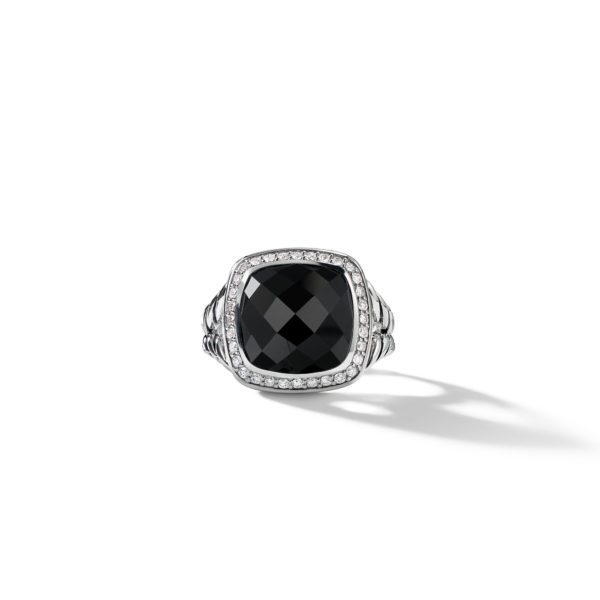 A silver ring featuring a large, square-shaped black gemstone set in the center, surrounded by small clear stones on a detailed band. The ring casts a shadow on a white background.