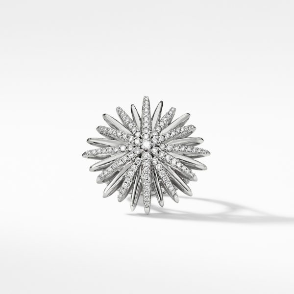 A close-up of a silver spiked starburst brooch adorned with numerous small diamonds, creating a sparkling, radiant effect. The brooch is set against a simple white background, emphasizing its intricate details and reflective surfaces.