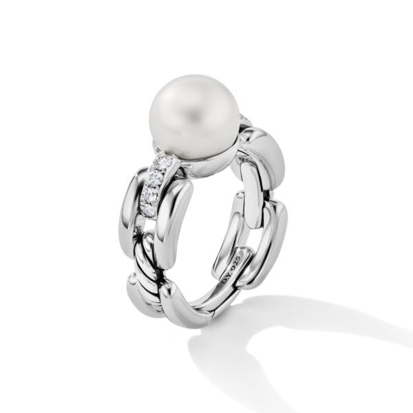 A silver ring with a chain-like band design features a prominent, large pearl as its centerpiece. The band is adorned with small, sparkling diamonds leading up to the pearl. The ring is photographed against a plain white background.