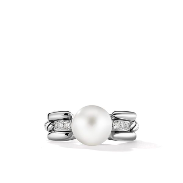 A silver ring featuring a central, elegant white pearl flanked by small diamonds embedded in a smooth, polished setting. The ring displays a modern, sophisticated design with a blend of curves and straight lines.