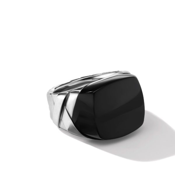 A silver ring with a large rectangular black stone centerpiece, displayed on a white background with a subtle shadow to the right. The ring features an intricate design with a polished finish.