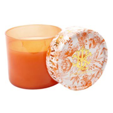 The Lux Fragrances Grapefruit Liddle Candle - 15oz features an orange-colored candle in a transparent orange glass holder with a removable lid. The lid is adorned with a white and shades of orange floral design, centered by a yellow monogram. The candle itself appears unused.