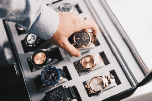 A man places a watch inside a travel jewelry case