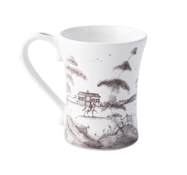 The Juliska Country Estate Mug - Flint is a white ceramic mug adorned with a black pastoral scene showcasing trees, a small house, and two human figures. The artwork is intricate, featuring detailed shading that imparts a vintage feel. The mug also boasts a curved handle and gently flares near the lip.