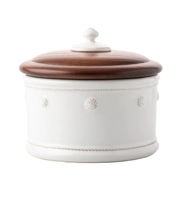 The Juliska Berry & Thread Dog Treat Canister in Whitewash is a round, white ceramic container adorned with decorative dots and stitch-like patterns along the sides. It features a smooth, dark brown wooden lid topped with a small knob handle.