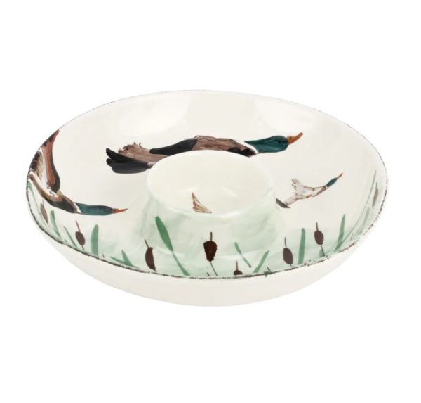 The Vietri Wildlife Chip and Dip Platter - Mallard is a round ceramic serving platter adorned with painted mallard ducks flying over green cattails. This white plate features a central dip compartment and showcases beautiful nature-inspired artwork.