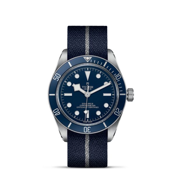 The TUDOR Black Bay Fifty-Eight wristwatch showcases a nautical theme with its blue dial and white hour markers and hands. It features a fabric strap with a stripe, a stainless steel case, and comes equipped with a rotating bezel.