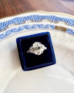 oval three-stone engagement ring on a porcelain plate