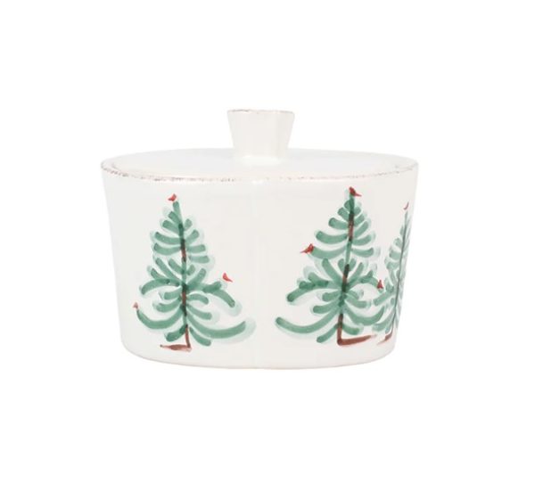 The Vietri Lastra Holiday Lidded Sugar is a white ceramic container featuring a lid and decorated with green trees and small red birds around its exterior. The top handle is rounded, giving the container a slightly weathered, rustic appearance.