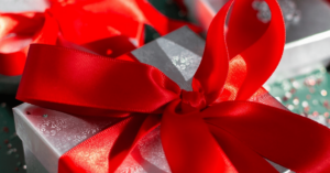 Holiday jewelry in Bromberg’s signature silver gift box with red bow on a glitter background