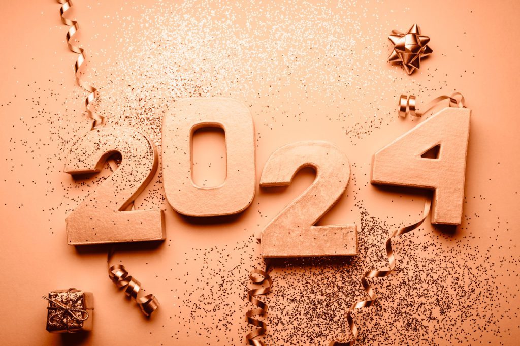 Golden digits spelling 2024 with glitter and decorations nearby, toned in Peach Fuzz: Pantone Color of the Year.