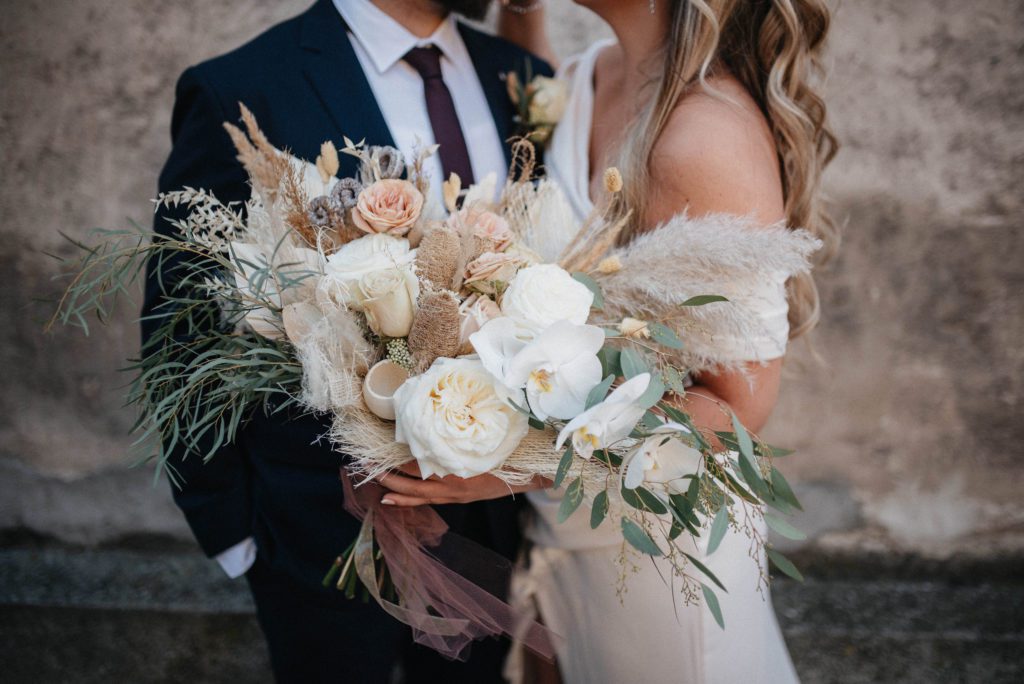 Cropped shot of a bride and groom with a large bouquet in the foreground.
