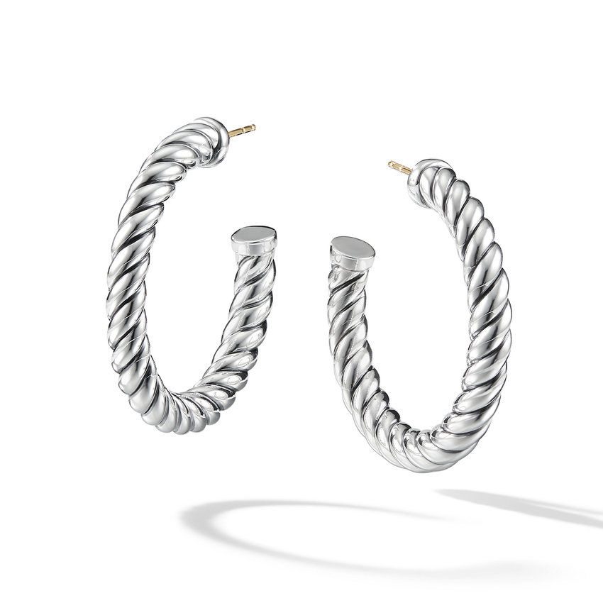 A pair of silver sculpted hoop earrings from David Yurman float elegantly with a white background.