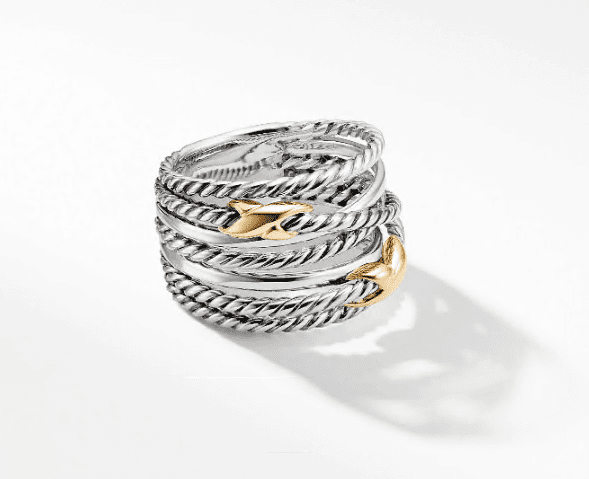 The PAVE CROSSOVER 2 "X" RING features an elegant design with multiple intertwined silver bands and exquisite gold accents shaped like a whale's tail. The ring casts a soft shadow on a white background.