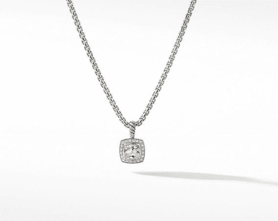 The 7MM CUSH PETITE ALBION silver necklace showcases a chain adorned with an exquisite square-shaped pendant. This pendant features a clear gemstone at its center, encircled by smaller stones that produce a stunning halo effect. The jewelry is set against a plain white backdrop, emphasizing its simplicity and elegance.