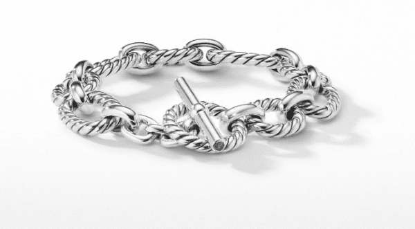 The 12.5MM Cushion Link Chain Bracelet features intricately twisted silver links connected by smooth loops. It includes a toggle clasp for fastening, enhancing its elegant and sophisticated design, and is displayed against a plain white background.