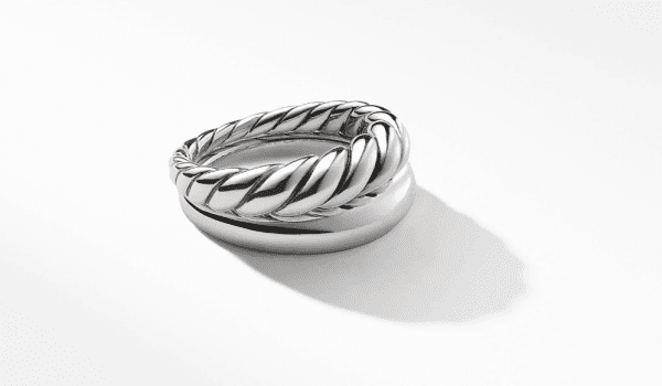 A close-up image of the PURE FORM SET OF 2 STACK RINGS on a white surface. The top ring showcases a twisted rope design, while the bottom one boasts a simple and smooth finish. Soft shadows of both rings are cast on the surface.