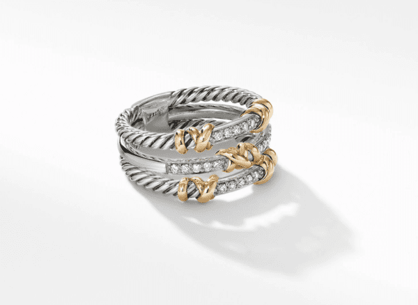 The PETITE HELENA 3 ROW RING showcases intertwined bands of silver and gold. The silver bands feature a rope-like texture, while the polished gold accents form elegant knotted details. Small, sparkling diamonds are embedded within the ring, adding an extra touch of sophistication.