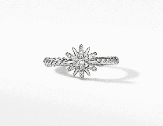 Introducing the PETITE STARBURST RING, a stunning silver ring featuring a twisted band and a central starburst design, embellished with small, sparkling diamonds. This elegant piece of jewelry is showcased against a plain white background.