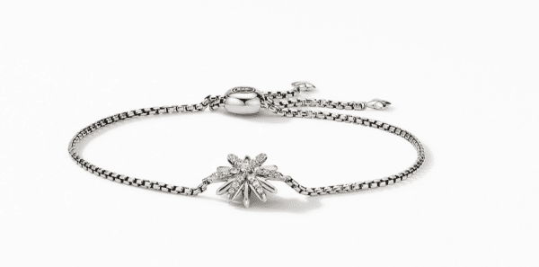 Introducing the STARBURST CHAIN BRACELET: a delicate silver chain bracelet featuring a central starburst design adorned with small sparkling crystals. The bracelet includes an adjustable clasp and a dangling charm. The design is beautifully showcased against a plain white background.