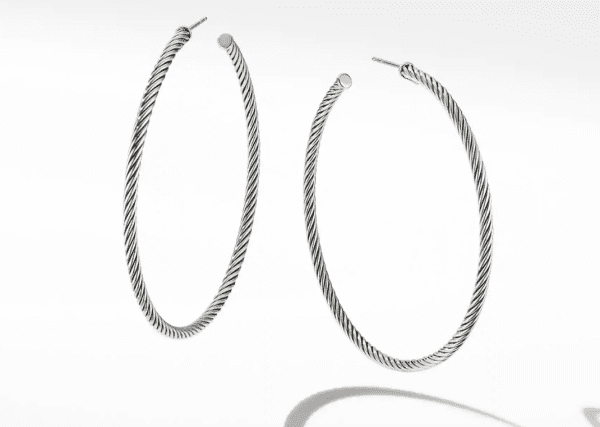 A pair of 2.5" CABLE HOOPS earrings is shown, featuring large, twisted silver hoops with post backings. The earrings are intricately designed with a rope-like texture and cast subtle shadows on a white background, emphasizing their circular shape.