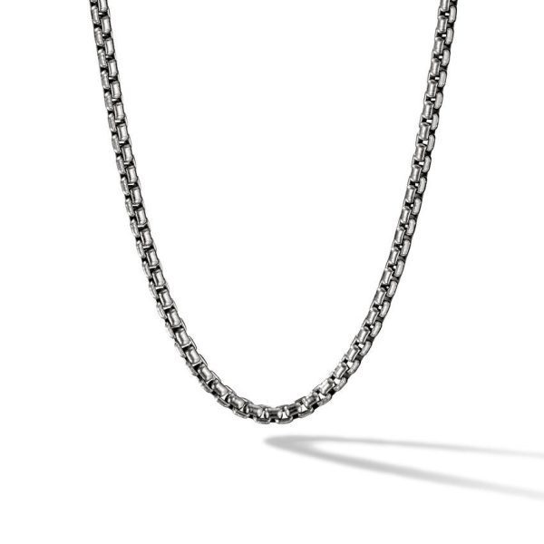 A close-up image of the 4MM MENS BOX CHAIN, a stainless steel necklace with a box link design. The chain is displayed against a white background with a faint shadow beneath it, accentuating its shiny, metallic finish.