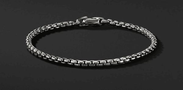 A close-up image of the 4MM BOX CHAIN BRACELET, showcasing its intricate silver box chain design against a black background. The bracelet features a secure clasp closure.