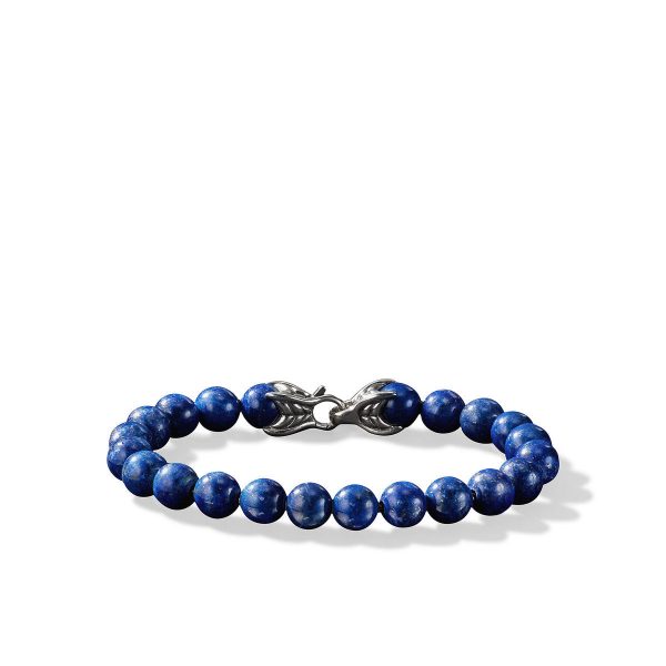 The 8MM SPIRITUAL BEAD bracelet, featuring polished blue beads marbled with white flecks, is displayed on a white background. It is secured with an intricate metallic clasp designed to resemble two leaf-like shapes.