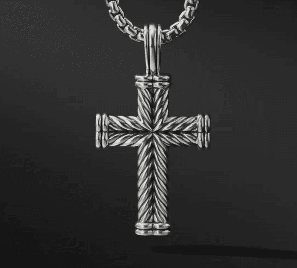 A LARGE CHEVRON CROSS pendant with intricate rope-like detailing hangs from a matching chain against a dark background. The pendant features a textured design, creating a sophisticated and elegant appearance.