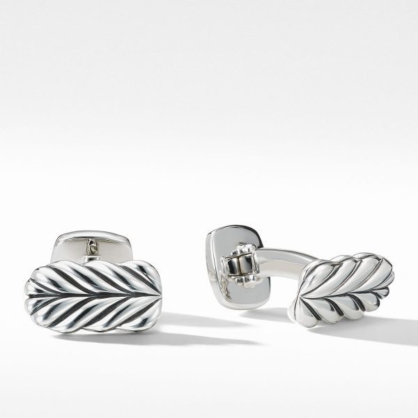 A pair of CHEVRON CUFFLINKS sits against a white background. Each cufflink features a leaf-like design with intricate detailing, showcasing a wavy, textured pattern. The cufflinks are reflective and polished, emphasizing their elegant and sophisticated appearance.