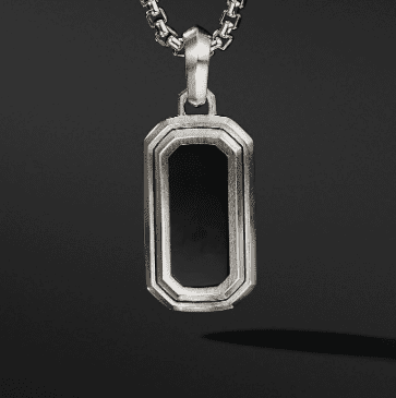 The DECO AMULET is a silver chain necklace featuring a rectangular pendant with beveled edges, enclosing a black rectangular centerpiece, set against a dark background.