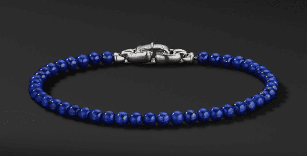 The 4MM SPIRITUAL BEAD bracelet, showcasing a strand of deep blue round beads with a silver clasp, is displayed against a dark background. The symmetrical arrangement of the beads and the sleek design emphasize its elegance and simplicity.