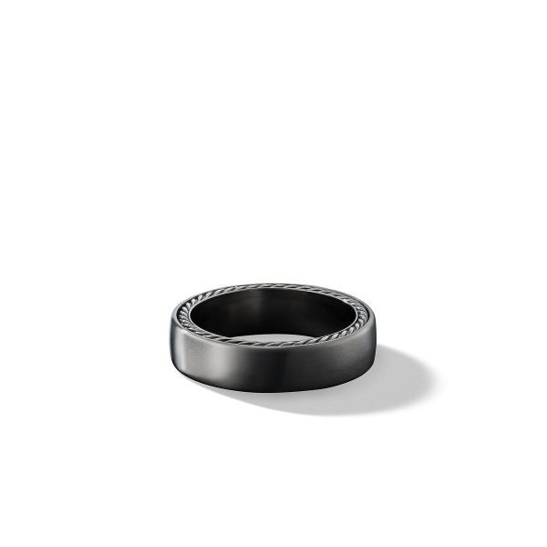 The 6MM STREAMLINE BAND is a sleek black ring featuring a smooth, matte finish. Its simple design is accentuated by a subtle rope-like texture engraved along the outer edge, casting a soft shadow on the white background.