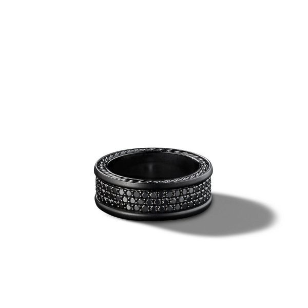 The 8.5MM 3 ROW PAVE BAND showcases a sleek black exterior with a stunning textured, beaded design encircling its middle. The ring casts a gentle shadow on a plain white background, emphasizing its glossy finish and intricate details.