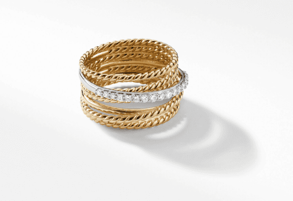 The WIDE CROSSOVER RING features multiple intertwined gold bands, with one band accentuated by small diamonds that add a touch of sparkle. The ring is set against a plain white background.