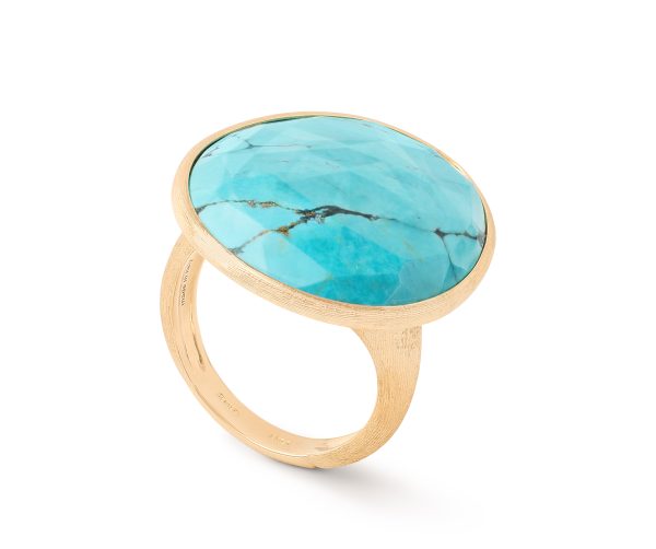 The Marco Bicego Lunaria Turquoise Cocktail Ring showcases a large, round turquoise stone with natural veining. The smooth and polished gemstone is set in a simple, elegant gold band. The ring is angled slightly to highlight the details of both the band and the exquisite stone.