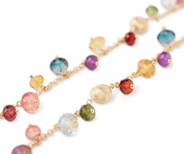 A close-up of the Marco Bicego Africa Mixed Gemstone Necklace showcases an array of vibrantly colored gemstones, such as red, blue, green, purple, and gold beads. These round and faceted gems are connected by a delicate gold chain and softly reflect the light.