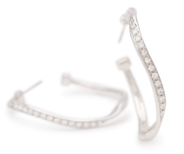 The Marco Bicego Marrakech Diamond Twist Hoop Earrings feature an elegant silver design with a wavy pattern, accentuated by small, sparkling diamonds along the outer edge, and are showcased against a plain white background.